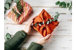 Hands offering a gift wrapped in organic fabric