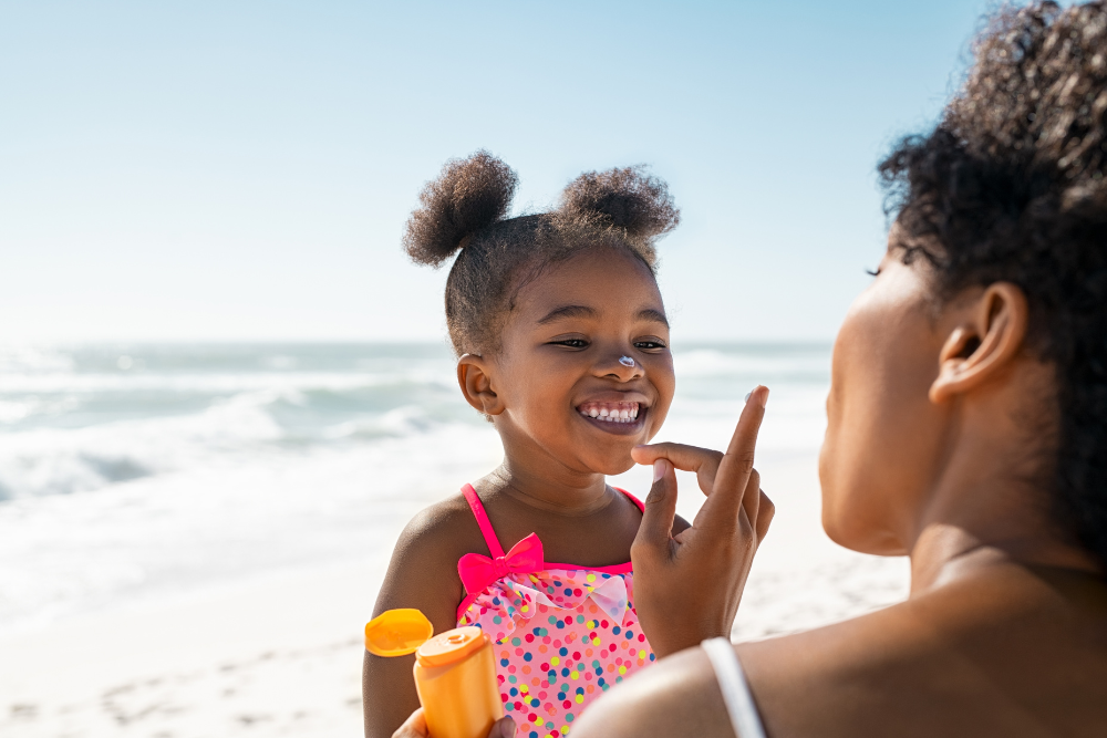 mother applying sunscreen to young daughter i