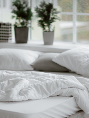 an unmade bed with white organic duvets