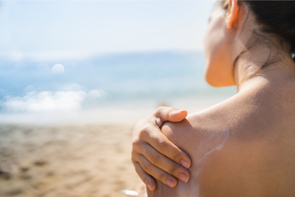 lady rubbing organic sunscreen into her shoulder viewed from behind