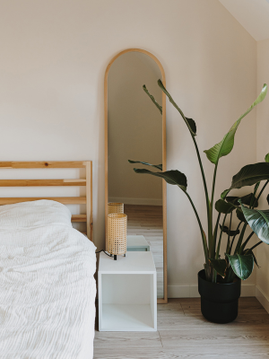 a calming bedroom with large plants and neutral bedlinen